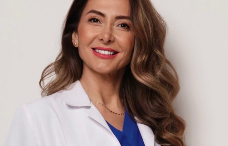 Doç. Dr. Ebru Zülfikaroğlu, beyaz hekim önlüğü ve mavi üstüyle profesyonel bir duruş sergileyen, uzun dalgalı kahverengi saçlara sahip bir kadın sağlık profesyoneli olarak görünüyor. Arka planın sade ve açık tonlarda olması, portreyi daha da öne çıkarıyor ve kendisinin uzmanlık alanını yansıtan güven veren bir ifade oluşturuyor.