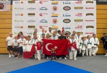 Down Judo Millî Takımımız ile teknik kadro Türk bayraklarını ellerinde tutuyor, kazanılan kupa ise ön tarafta yerde durmakta.