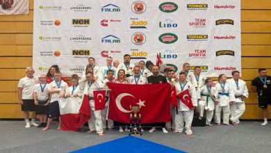 Down Judo Millî Takımımız ile teknik kadro Türk bayraklarını ellerinde tutuyor, kazanılan kupa ise ön tarafta yerde durmakta.