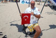 Engelli sporcu Ömer Kalay, plajda Türk bayrağı tutarak poz veriyor.