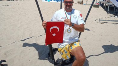 Engelli sporcu Ömer Kalay, plajda Türk bayrağı tutarak poz veriyor.