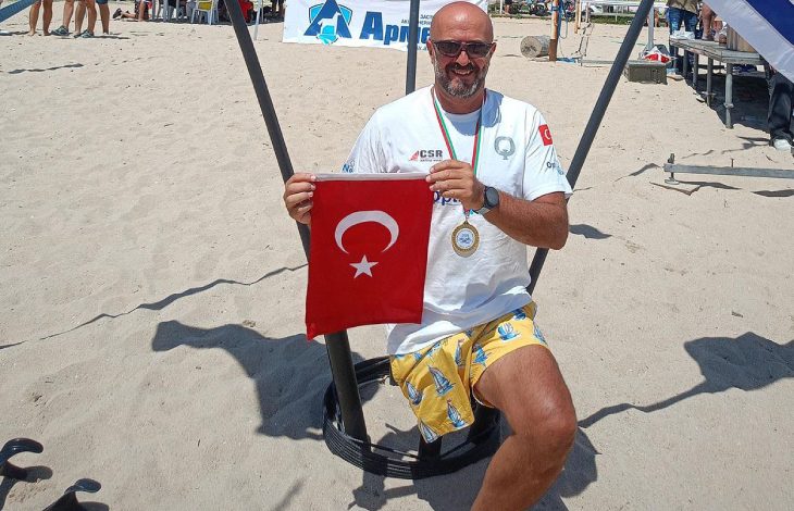 Engelli sporcu Ömer Kalay, plajda Türk bayrağı tutarak poz veriyor.