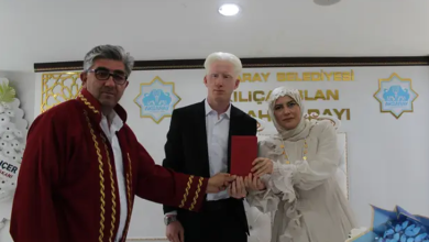 Görselde, nikâh töreninde görme engelli çift yan yana dururken nikâh görevlisiyle birlikte evlilik cüzdanını tutuyor. Arka planda Aksaray Belediyesi logosu ve nikâh salonuna ait yazılar görülüyor.