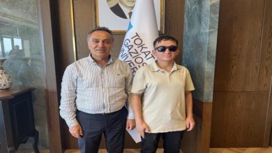 Görme engelli öğrenci Taha Gül, Tokat Gaziosmanpaşa Üniversitesi Rektörü Prof. Dr. Fatih Yılmaz ile beraber yan yana poz veriyor.