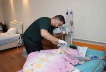 Murat Tayam, yatağında yatan annesine tıbbi müdahalede bulunurken görülüyor.