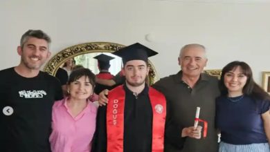 Otizmli Öğrenci Deniz Köse, mezuniyet kıyafetiyle ailesi ile ev ortamında poz veriyor.