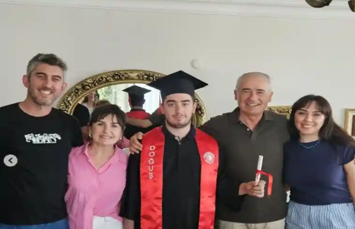 Otizmli Öğrenci Deniz Köse, mezuniyet kıyafetiyle ailesi ile ev ortamında poz veriyor.