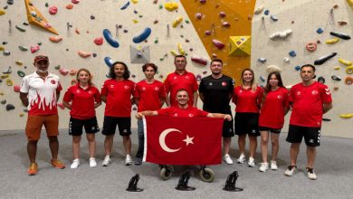 Fotoğrafta, tırmanış duvarının önünde kırmızı-beyaz Türk milli takım formaları giyen bir grup sporcu ve görevli, ortada Türk bayrağı tutan tekerlekli sandalyedeki bir sporcu ile birlikte gururla poz veriyor.