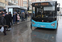 Fotoğrafta, yağışlı havada bir şehir içi otobüsü durakta yolcu almak üzere bekliyor. Durakta otobüsü bekleyen vatandaşlar görülürken, otobüsün ön ekranında "Fatih" hattı yazıyor. Yolda ıslak zemin ve çevredeki binalar dikkat çekiyor.