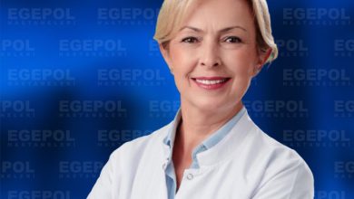 Kısa açık renk saçlı ve gülümseyen Uzm. Dr. Tuğba Emüroğlu, beyaz hekim önlüğüyle kollarını çapraz şekilde bağlamış halde görülüyor. Arka planda mavi zemin üzerinde tekrarlanan “EGEPOL HASTANELERİ” yazıları yer alıyor. Genel görünüm profesyonel, güven veren ve kurumsal bir sağlık ortamını yansıtıyor.