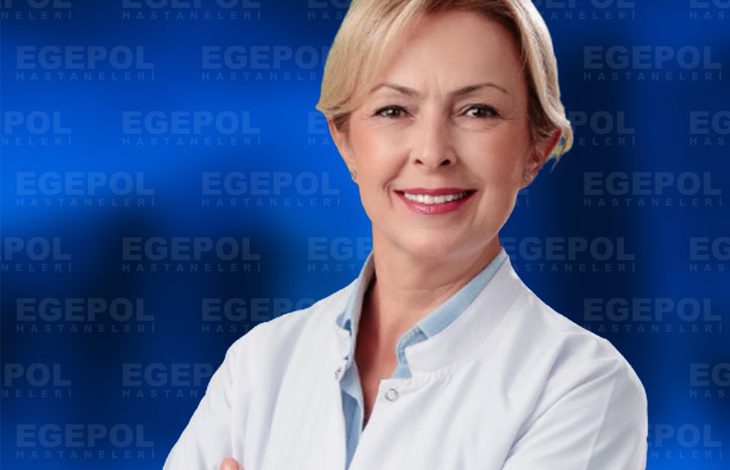 Kısa açık renk saçlı ve gülümseyen Uzm. Dr. Tuğba Emüroğlu, beyaz hekim önlüğüyle kollarını çapraz şekilde bağlamış halde görülüyor. Arka planda mavi zemin üzerinde tekrarlanan “EGEPOL HASTANELERİ” yazıları yer alıyor. Genel görünüm profesyonel, güven veren ve kurumsal bir sağlık ortamını yansıtıyor.