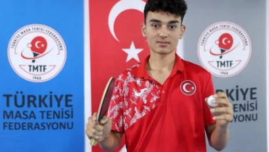 Görselde, Ebubekir İnce kırmızı Türkiye formasıyla elinde masa tenisi raketi ve top tutarak kameraya bakıyor. Arka planda Türk bayrağı ile Türkiye Masa Tenisi Federasyonu logolarının bulunduğu panolar yer alıyor.