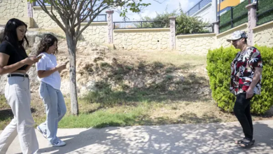 Görme engelli bir birey, açık alanda karşısındaki iki genç kadınla birlikte yürüyor.