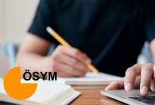Görselin üst bölümünde, ahşap bir çalışma masasında ders çalışan veya sınav hazırlığı yapan siyah tişörtlü bir adayın elleri ve çalışma alanı yakın plandan görülüyor. Sol eliyle sarı bir kurşun kalemi tutarak deftere yazı yazan adayın sağ eli ise gri renkli dizüstü bilgisayarın klavyesinin üzerinde duruyor. Görselin sol alt köşesinde ÖSYM'nin turuncu renkli stilize amblemi ve siyah büyük harflerle "ÖSYM" yazısı yer alıyor.