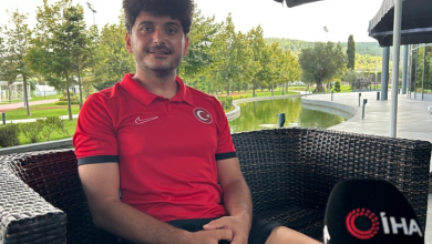 Görselin üst bölümünde, açık alandaki bir tesiste hasır koltukta oturarak röportaj veren milli ampute futbolcu Barış Telli yer alıyor. Kıvırcık koyu renk saçlı ve hafif sakallı olan Telli, göğsünde Türk bayrağı arması bulunan kırmızı milli takım polo tişörtü ve siyah şort giymiş halde tebessüm ederek kameraya bakıyor. Sağ alt köşede İhlas Haber Ajansı (İHA) logolu mikrofon ucu görülürken; arka planda ise yeşil ağaçlar, çimlik alan, yapay gölet/havuz ve modern tesis yapıları seçiliyor.