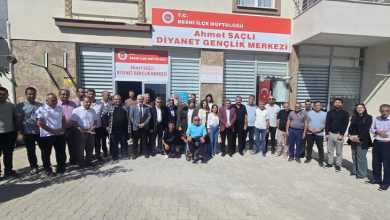 rselin üst bölümünde, T.C. Besni İlçe Müftülüğü Ahmet Saçlı Diyanet Gençlik Merkezi binasının önünde toplanarak toplu hatıra fotoğrafı çektiren kalabalık bir heyet ve vatandaş grubu yer alıyor. Binanın girişinde kırmızı-beyaz tabelada merkez adı okunurken, ön cephedeki camların önünde takım elbiseli protokol üyeleri, kadın ve erkek katılımcılar geniş bir sıra halinde dizilmiş durumda. Topluluğun tam ortasında mavi tişörtlü bedensel engelli bir birey tekerlekli sandalyesinde oturarak objektife bakarken, iki yanında ve arkasında yerel yetkililer, din görevlileri ve sivil katılımcılar kilit parke taşlı avluda yan yana durarak gülümsüyor.
