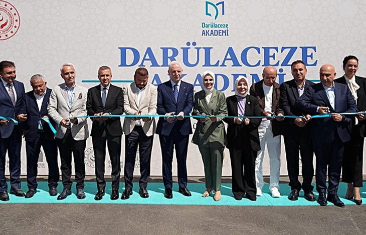 Görselin üst bölümünde, açık havada kurulan tören sahnesinde yan yana dizilmiş protokol heyeti, ellerindeki makaslarla açılış kurdelesini keserken yer alıyor. Arka plandaki beyaz fonda büyük harflerle "DARÜLACEZE AKADEMİ" yazısı, kurumun logosu ve sol üst köşede T.C. Aile ve Sosyal Hizmetler Bakanlığı amblemi görülüyor. Ön planda takım elbiseli bürokratlar, yerel yöneticiler ve heyetteki kadın yetkililer, gergin tutulan açık mavi açılış kurdelesini hep birlikte keserek tebessümle kameraya poz veriyor.