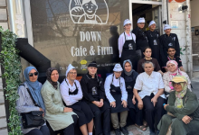 Görselde, Down Cafe & Fırın adlı işletmenin önünde bir grup insan toplu halde poz veriyor. Önlük ve aşçı boneleri giyen bazı çalışanlar arasında Down sendromlu bireyler de yer alıyor.