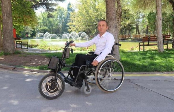 Anadolu Üniversitesi personeli Recep Çetin, motor aparatlı tekerlekli sandalyede oturuyor.