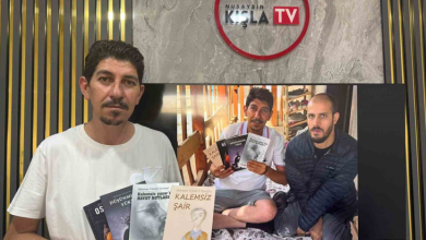 Görselde, beyaz tişörtlü bir erkek elinde dört kitap tutarak kameraya bakıyor. Arkasındaki ekranda aynı kişinin, yatakta oturan başka bir erkekle birlikte kitapları gösterdiği bir fotoğraf yer alıyor. Arka duvarda Nusaybin Kışla TV logosu görülüyor.