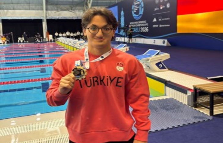 Para Yüzücü Turgut Aslan Yaraman, mercan renkli uzun kollu, Türkiye yazılı tişörtle ve boynunda bulunan madalyayla poz veriyor.