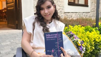 Tekerlekli sandalyesinde, açık havada otururken gülümseyen bir kadın görülüyor. Yanında çiçeklerle çevrili küçük bir bahçe ve taş duvarlı bir yapı bulunuyor. Elinde koyu lacivert kapaklı bir kitap tutuyor. Kitabın üzerinde “hikayem bitmedi”, “İrem MENSURE” ve “Hayat tekerlekli sandalyede bile güzeldir.” ifadeleri yer alıyor. Yazarın duruşu, yüzündeki sıcak ifade ve kitabını gururla tutuşu; yaşam enerjisini, üretkenliğini ve ilham veren bir hikâye anlatıcısı olduğunu hissettiriyor.