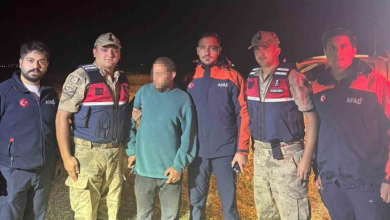 Görselin üst bölümünde, gece vakti açık arazide arama kurtarma ekiplerinin ortasında duran bulunan genç erkek yer alıyor. Ortada duran ve yüzü buzlanmış olan yeşil svetşörtlü ve gri pantolonlu vatandaşın her iki yanında, kamuflaj üniformalı ve kurşun geçirmez yelekli Jandarma personeli ile lacivert-turuncu AFAD montları giymiş arama kurtarma görevlileri bulunuyor; ekipler karanlık yayla zemininde gencin yanında güvenli bir şekilde dizilerek kameraya bakıyor.