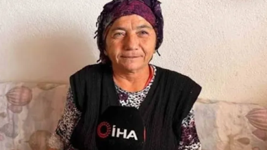 Görselde, mor bir başörtüsü takan Keziban Çiçeklioğlu desenli bir koltukta oturuyor. Üzerinde koyu renk bir yelek ve desenli bir bluz bulunuyor. Önünde, röportaj yapıldığını gösteren İHA logolu bir mikrofon yer alıyor. Arka planda açık renk bir duvar görülüyor. Kişi, sakin ve içten bir ifadeyle kameraya doğru konuşuyor gibi görünüyor.