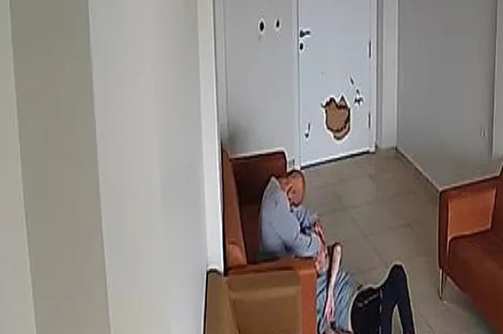 Görselin üst bölümünde, bir rehabilitasyon merkezinin bekleme alanını yukarıdan gören güvenlik kamerası kaydından bir an yer alıyor. Kahverengi deri koltuğun önünde, gri eşofmanlı ve siyah pantolonlu bir kişi yerde sırtüstü hareketsiz şekilde yatarken, hemen yanındaki gri üst giymiş bir adamın koltuğun kenarından eğilerek yerde yatan bireye müdahale ettiği veya üzerine kapandığı görülüyor. Arka plandaki beyaz renkli kapının üzerinde yumruk ya da darbe sonucu oluşmuş büyük bir delik ve hasar dikkat çekiyor.