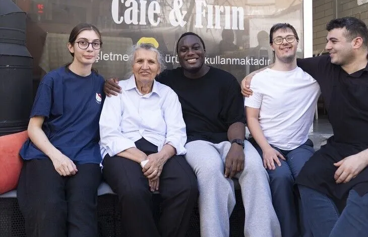 Görselin üst bölümünde, bir "Cafe & Fırın" tabelasının önünde yan yana oturarak samimi bir şekilde poz veren beş kişilik neşeli bir grup yer alıyor. Soldan sağa doğru gözlüklü mavi tişörtlü bir genç kadın, ortada beyaz gömlekli yaşlı bir kadın, onun yanında siyah tişörtlü gülümseyen siyahi bir genç, gözlüklü beyaz tişörtlü Down sendromlu bir genç ve en sağda siyah tişörtlü başka bir genç çalışan yan yana oturuyor. Arkadaki cam vitrin üzerinde "Cafe & Fırın" yazısı ve bilgilendirici ibareler seçiliyor.