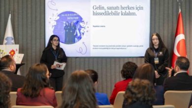 Görselde, iki genç kızın bir sunum yaptığı ve karşılarında onları dinleyen bir topluluğun bulunduğu bir etkinlik görülüyor; arka plandaki ekranda ise sanat ve yaratıcılıkla ilgili bir sunum yer alıyor.