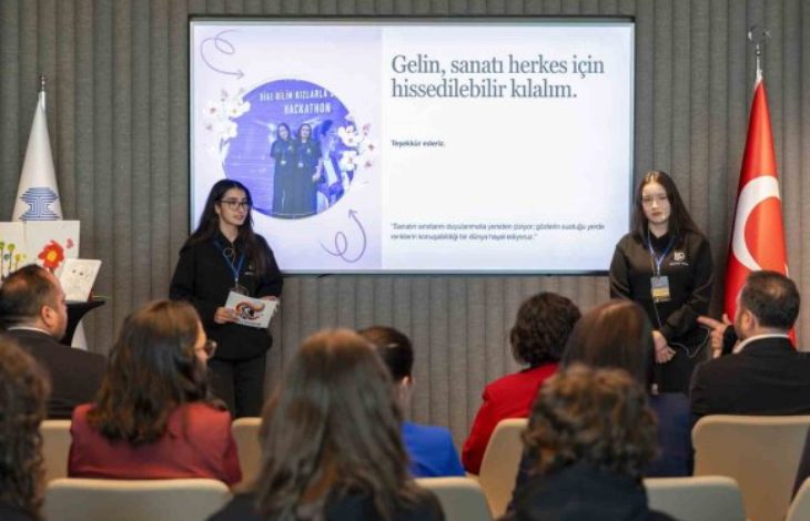 Görselde, iki genç kızın bir sunum yaptığı ve karşılarında onları dinleyen bir topluluğun bulunduğu bir etkinlik görülüyor; arka plandaki ekranda ise sanat ve yaratıcılıkla ilgili bir sunum yer alıyor.
