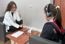 Görselde, klinik veya muayenehane ortamında bir uzman ile çocuk arasında gerçekleştirilen bir işitme testi seansı yer alıyor.