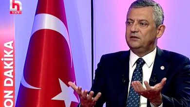 Stüdyoda takım elbise ve kravatıyla oturan Yeni Parti Genel Başkanı, canlı yayında konuşurken iki elini hafifçe yukarı doğru açmış şekilde jest yapıyor. Arka planda mor ve pembe tonlarda aydınlatılmış bir stüdyo atmosferi bulunuyor. Sağ tarafta büyük bir Türk bayrağı yer alıyor. Sol tarafta kırmızı zemin üzerinde beyaz harflerle “SON DAKİKA” yazısı ve onun üstünde kanalın logosu görünüyor. Genel başkan, ciddi ve odaklanmış bir ifadeyle gündeme dair açıklama yapıyor gibi görünüyor.