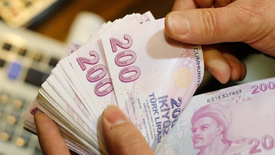 Görselin üst bölümünde, bir kişinin elleri arasında tuttuğu ve saydığı deste hâlindeki pembe renkli 200 Türk Lirası banknotlar yer alıyor. Ön plandaki banknotun üzerinde Yunus Emre portresi ve "200 İKİ YÜZ TÜRK LİRASI" ibaresi net bir şekilde görülürken, kişinin parmakları desteyi hafifçe aralamış vaziyette duruyor; sol arka planda ise ofis ortamını çağrıştıran hesap makinesi veya klavye tuşları flu olarak seçiliyor.