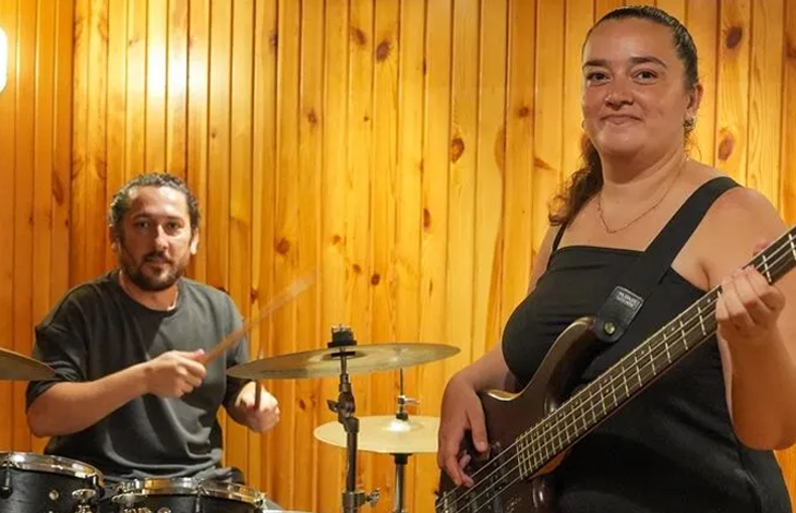 Ahşap kaplı bir stüdyo duvarı önünde müzik yapan bir kadın ve bir erkek görülüyor. Sağda duran siyah askılı bluzlu kadın hafifçe gülümseyerek bas gitar çalarken, solda siyah tişörtlü sakallı erkek bateri başında bagetleriyle çalmaya hazır halde kameraya bakıyor.