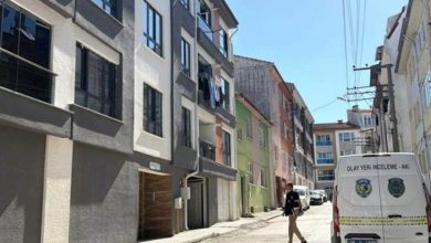 Dar bir mahalle sokağında, resmi görevli bir kişi olay yeri inceleme aracının yanında yürürken görülüyor. Çevrede çok katlı apartmanlar, balkonlar ve gündelik mahalle yaşamı dikkat çekiyor. Ortam sakin; görevlinin varlığı sokakta resmî bir inceleme yapıldığı izlenimi veriyor.