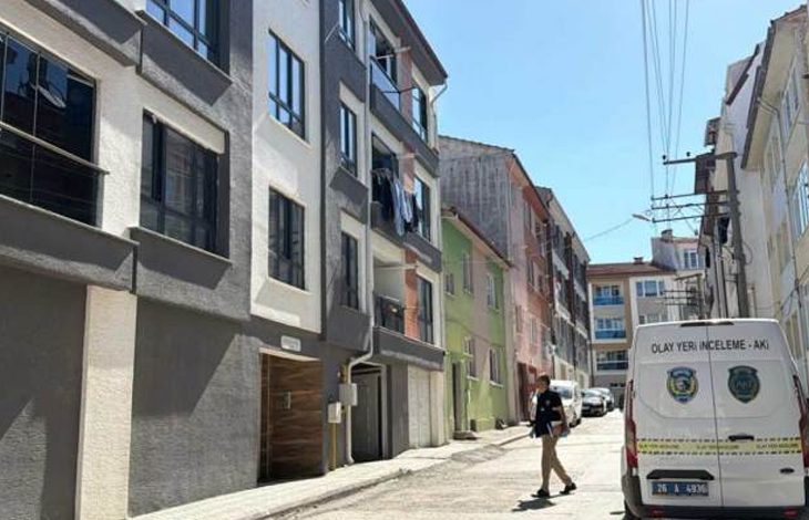 Dar bir mahalle sokağında, resmi görevli bir kişi olay yeri inceleme aracının yanında yürürken görülüyor. Çevrede çok katlı apartmanlar, balkonlar ve gündelik mahalle yaşamı dikkat çekiyor. Ortam sakin; görevlinin varlığı sokakta resmî bir inceleme yapıldığı izlenimi veriyor.