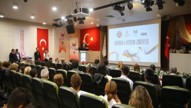 Adana 1. Otizm Zirvesinde, izleyici koltuklarında oturan katılımcılar kürsüde konuşma yapan kişiyi dinliyor.