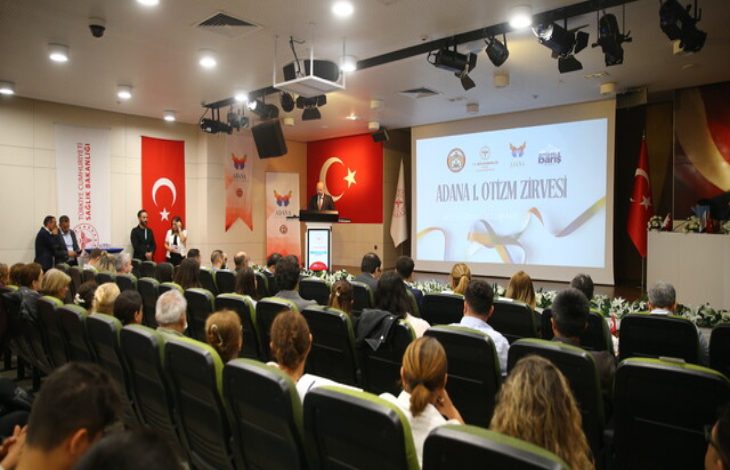 Adana 1. Otizm Zirvesinde, izleyici koltuklarında oturan katılımcılar kürsüde konuşma yapan kişiyi dinliyor.