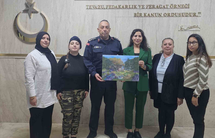 Görselde, kapalı bir mekanda yan yana duran altı kişilik bir grup yer almaktadır. Ortada askeri üniforma giymiş bir erkek ve yanında yeşil takım elbiseli bir kadın, ellerinde manzara resminin yer aldığı bir tabloyu birlikte tutmaktadır. Grubun diğer üyeleri ise onların yanında gülümseyerek poz vermektedir. Arka plandaki duvarda Atatürk'e ait bir yazı ve amblem yer almaktadır.
