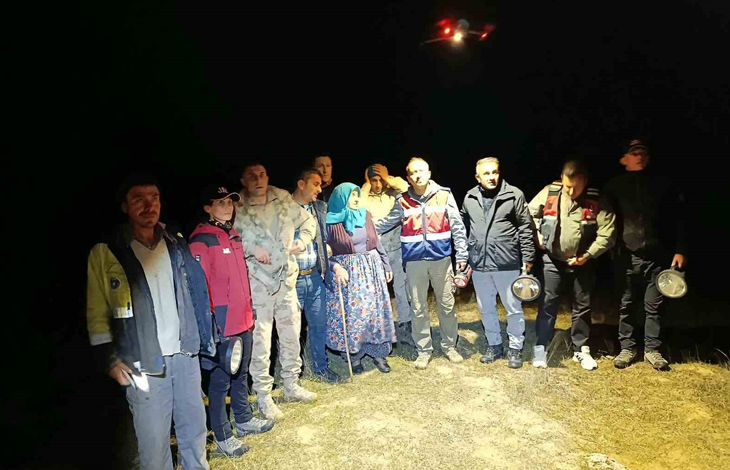 Görselin üst bölümünde, zifiri karanlık bir gecede arazide toplanmış arama kurtarma ekipleri, jandarma personeli ve bulunan zihinsel engelli kadın yer alıyor. Grubun tam ortasında, mavi başörtülü ve çiçekli basma etekli yaşlı kadın bastonuna dayanarak duruyor. Kadının çevresinde reflektörlü yelekler giymiş AFAD ve jandarma ekipleri, ellerinde büyük el fenerleri tutan kurtarma görevlileri ve kamuflajlı askerler sıralanıyor. Gökyüzünde ise arama çalışmalarında kullanılan, kırmızı ve beyaz ışıkları yanan bir insansız hava aracı (dron) havada asılı şekilde görülüyor.