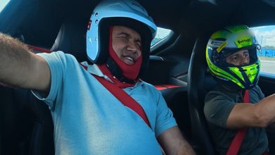 Görselde, otomobilin içinde kask takmış iki kişi görülüyor; öndeki kişi Levent Karadöl heyecanlı bir ifadeyle gözlerini kapatırken, Felipe Massa direksiyonda aracı kullanıyor.