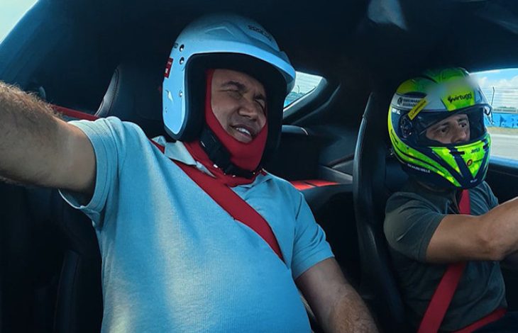 Görselde, otomobilin içinde kask takmış iki kişi görülüyor; öndeki kişi Levent Karadöl heyecanlı bir ifadeyle gözlerini kapatırken, Felipe Massa direksiyonda aracı kullanıyor.