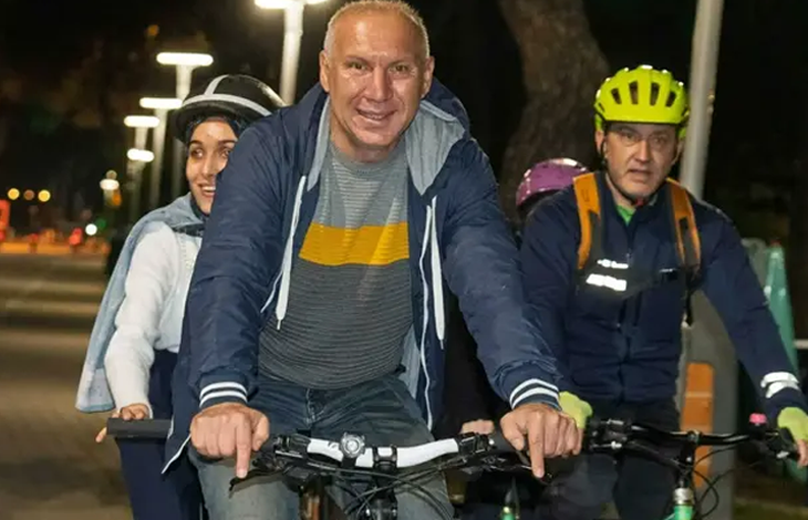 Görselde, akşam saatlerinde aydınlatılmış bir park yolunda bisiklet süren insanlar yer almaktadır. Önde ve ortada yer alan katılımcılar neşeyle pedal çevirirken, arkalarında kask takmış diğer bisikletçiler onlara eşlik etmektedir.