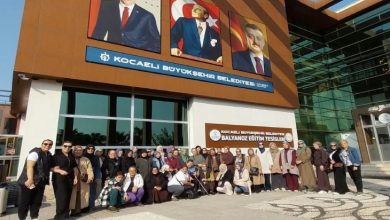 İşitme Engelli Kadınlar Derneği üyeleri Kocaeli Büyükşehir Belediyesi önünde birlikte poz veriyor.
