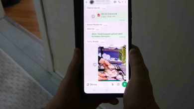 Görselde, bir kişinin elleri arasında tuttuğu akıllı telefon ekranında mesajlaşma uygulamasına ait bir sohbet ekranı görünmektedir. Ekran üzerinde yazışmalar ve pembe tonlarında bir fincan takımı görseli yer almaktadır.