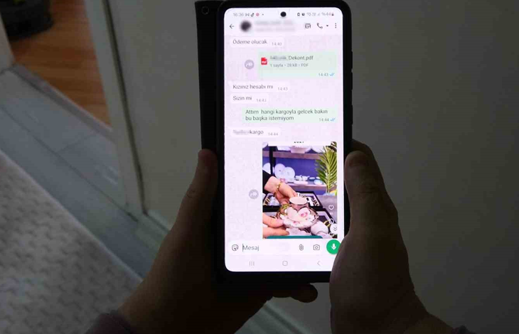 Görselde, bir kişinin elleri arasında tuttuğu akıllı telefon ekranında mesajlaşma uygulamasına ait bir sohbet ekranı görünmektedir. Ekran üzerinde yazışmalar ve pembe tonlarında bir fincan takımı görseli yer almaktadır.