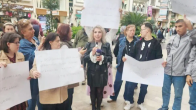 Görselin üst bölümünde, şehir merkezindeki kalabalık bir meydanda toplanarak basın açıklaması ve protesto gerçekleştiren engelli bireyler ile aileleri yer alıyor. Grubun ortasında siyah deri ceketli ve etekli bir kadın elindeki mikrofonla açıklama yaparken, arkasındaki ve yanındaki katılımcılar ellerinde beyaz protesto dövizleri taşıyor. Ön planda ve yanlarda duran gençler ile aileleri tepkilerini dile getirirken; arka planda yayalar, cadde üzerindeki mağazalar ve şehir binaları görülüyor.