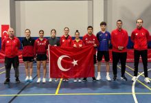 Özel Sporcular Para Masa Tenisi Millî Takımı ile teknik ekip beraber spor salonunda Türk bayrağıyla poz veriyor.